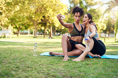 Buy stock photo Full length shot of two attractive young women posing for a selfie while in the park during the day
