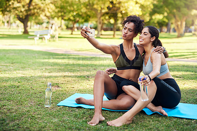 Buy stock photo Full length shot of two attractive young women posing for a selfie while in the park during the day