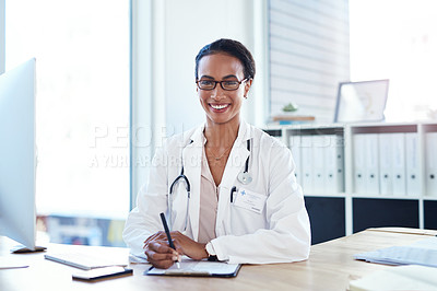 Buy stock photo Shot of a young doctor going over paperwork in her consulting room