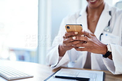 Buy stock photo Cropped shot of a doctor using a smartphone in her consulting room