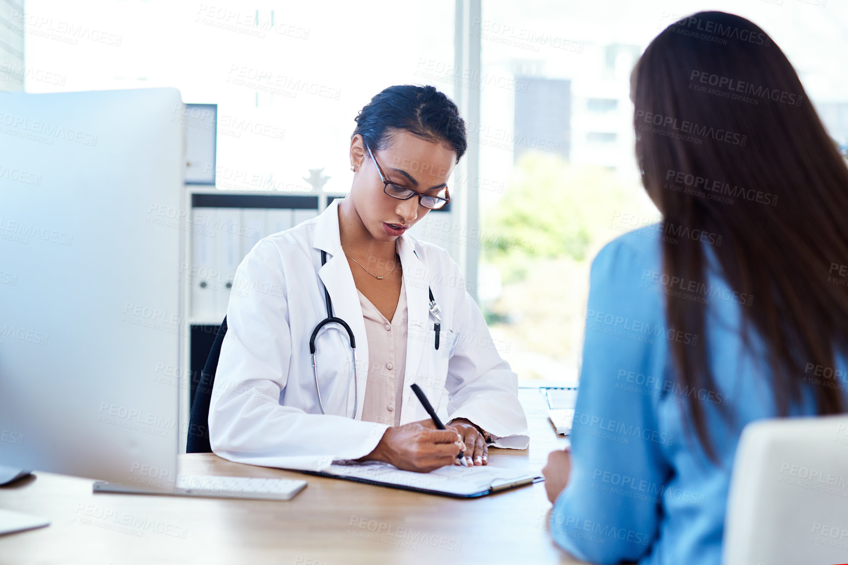 Buy stock photo Shot of a young doctor having a discussion with a patient in her consulting room