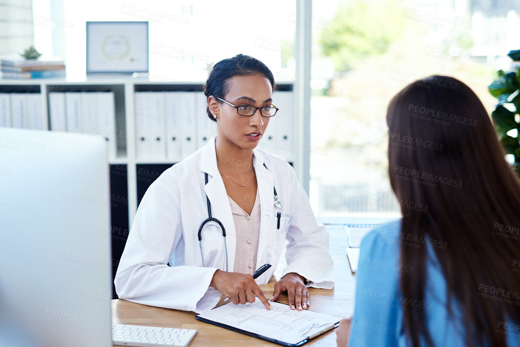 Buy stock photo Shot of a young doctor having a discussion with a patient in her consulting room