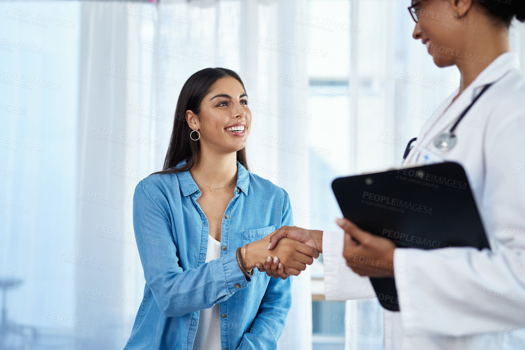 Buy stock photo Shot of a young doctor shaking hands with a patient in her consulting room