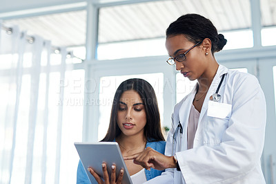 Buy stock photo Shot of a young doctor using a digital tablet during a consultation with her patient