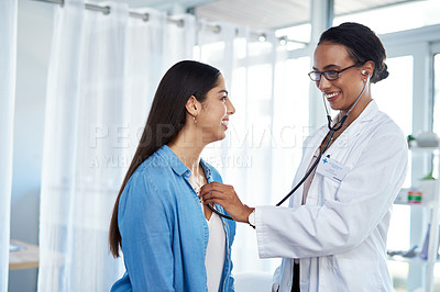 Buy stock photo Shot of a young doctor examining her patient with a stethoscope