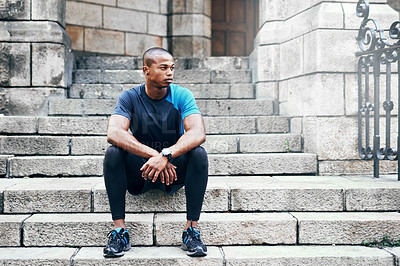 Buy stock photo Full length shot of a handsome young sportsman sitting down on a stairway outdoors in the city