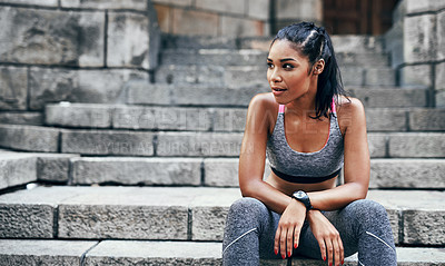 Buy stock photo Shot of an attractive young sportswoman sitting down on a stairway outdoors in the city