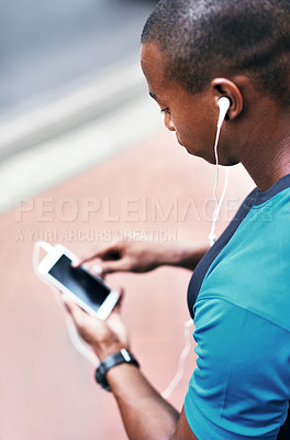 Buy stock photo High angle shot of a young man listening to music and using his cellphone while exercising outdoors in the city