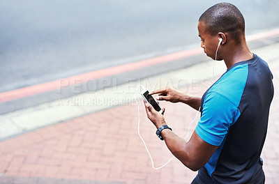 Buy stock photo High angle shot of a young man listening to music and using his cellphone while exercising outdoors in the city