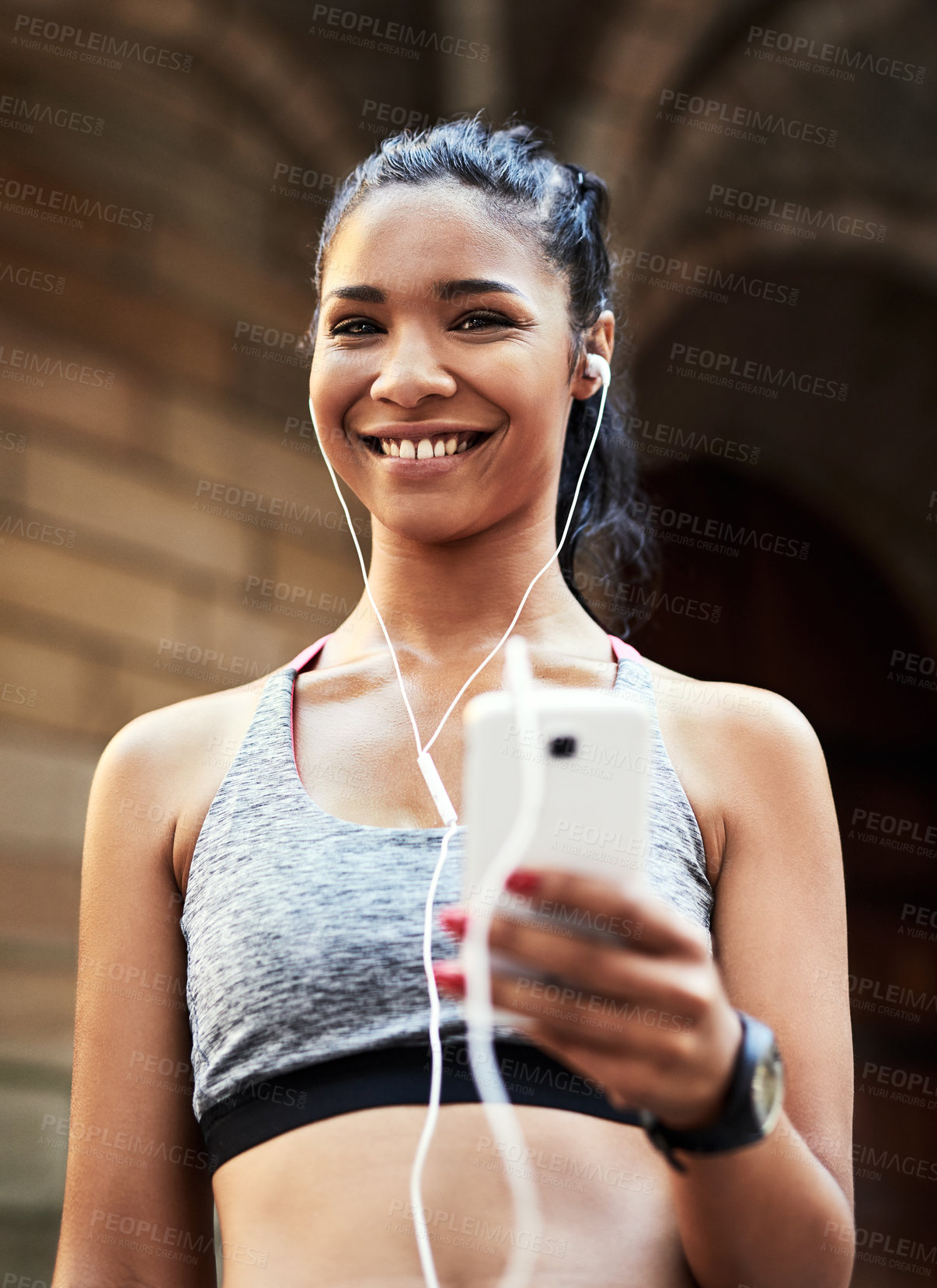 Buy stock photo Portrait of an attractive young woman listening to music and using her cellphone while exercising outdoors in the city