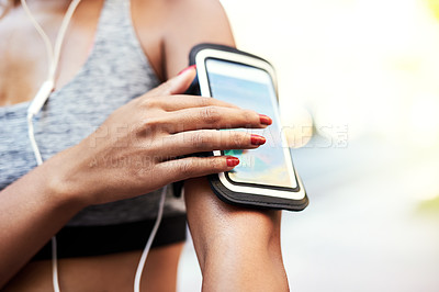 Buy stock photo Shot of an unrecognizable woman listening to music and using her cellphone while exercising outdoors in the city