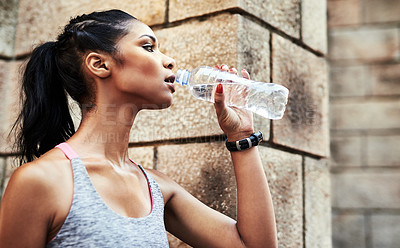 Buy stock photo Shot of an attractive young sportswoman drinking water from a bottle while exercising outdoors