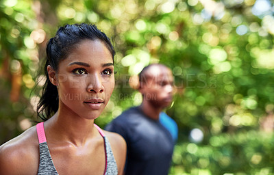 Buy stock photo Shot of an attractive young woman exercising outdoors with her boyfriend in the background
