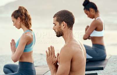 Buy stock photo Shot of a group of young people practicing yoga together outdoors