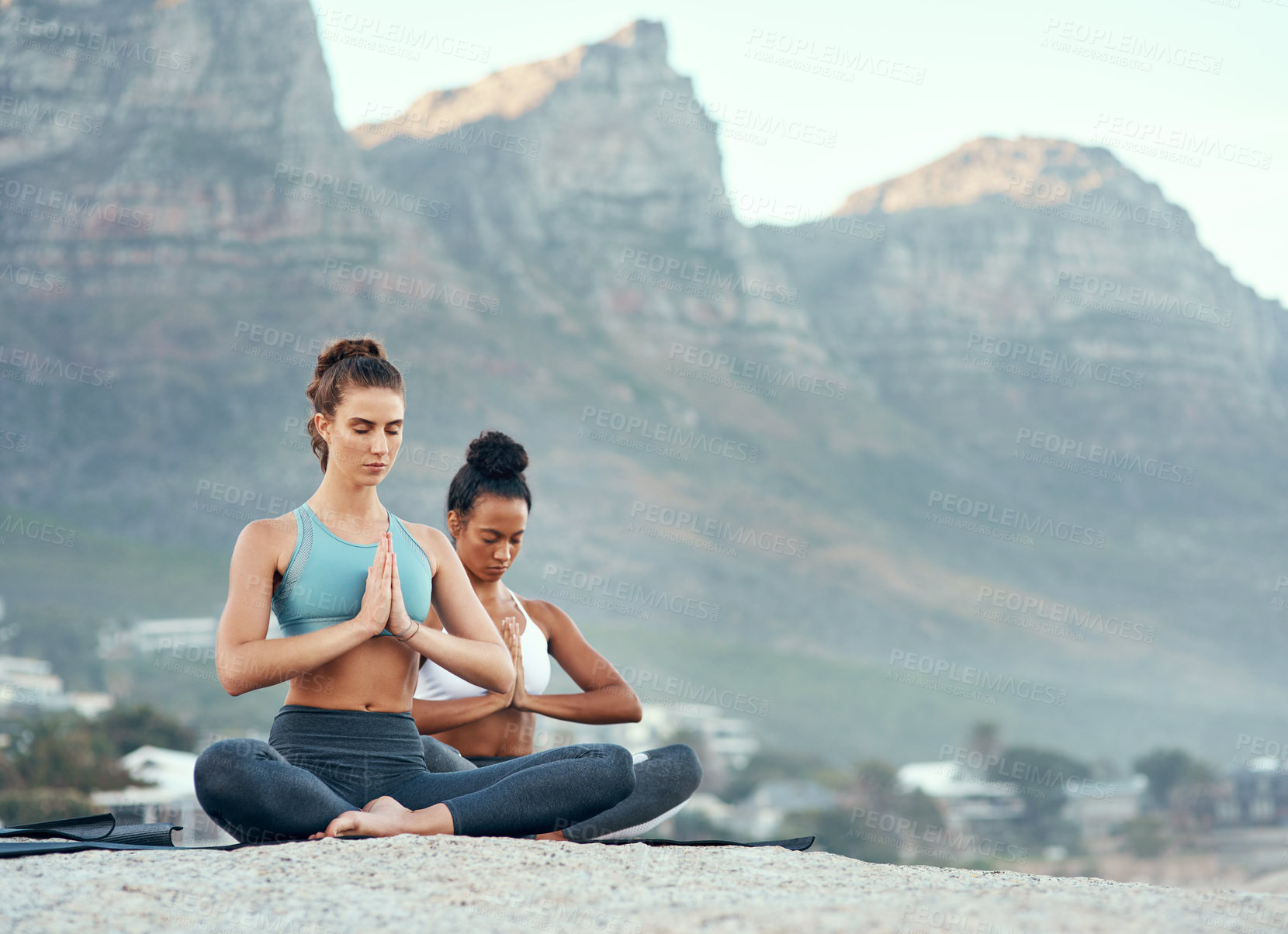 Buy stock photo Shot of two sporty young woman practicing yoga together outdoors