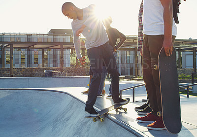 Buy stock photo Shot of a group of friends skating together on their skateboards at a skatepark