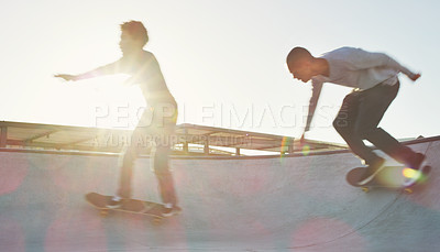 Buy stock photo Full length shot of two young men skating together on their skateboards at a skate park