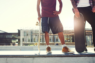 Buy stock photo Shot of two unrecognizable men skating together on their skateboards at a skate park