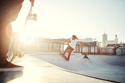 Buy stock photo Shot of two young men skating together on their skateboards at a skate park
