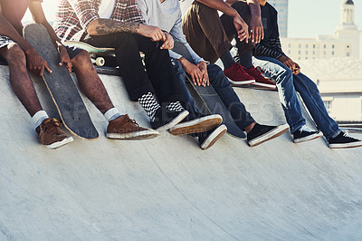 Buy stock photo Shot of a group of unrecognizable skaters sitting together on a ramp at a skatepark