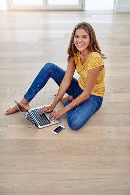 Buy stock photo Full body portrait of an attractive young woman sitting and using a laptop in the living room during the day