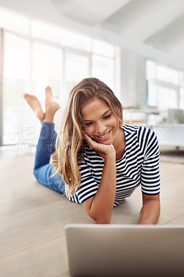 Buy stock photo Full body shot of an attractive young woman lying down and using a laptop in the living room