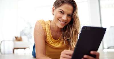 Buy stock photo Cropped portrait of an attractive young woman sitting and using a tablet in the living room during the day
