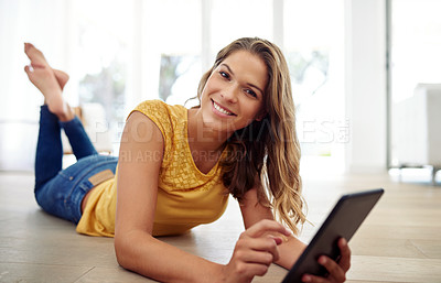 Buy stock photo Full body portrait of an attractive young woman sitting and using a tablet in the living room during the day