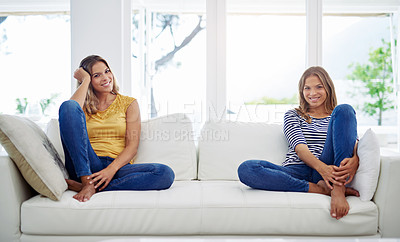 Buy stock photo Full length portrait of attractive young twin sisters relaxing on the sofa at home