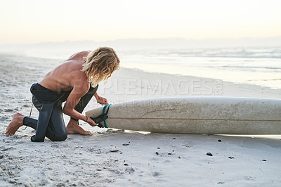 Buy stock photo Full length shot of a handsome young surfer getting his surfboard ready before going surfing at the beach