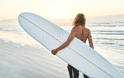 Buy stock photo Rearview shot of a young surfer walking with his surfboard at the beach
