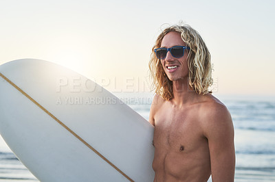 Buy stock photo Shot of a handsome young man carrying his surfboard at the beach