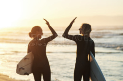Buy stock photo Rearview shot of a young couple joining hands for a high five while surfing at the beach