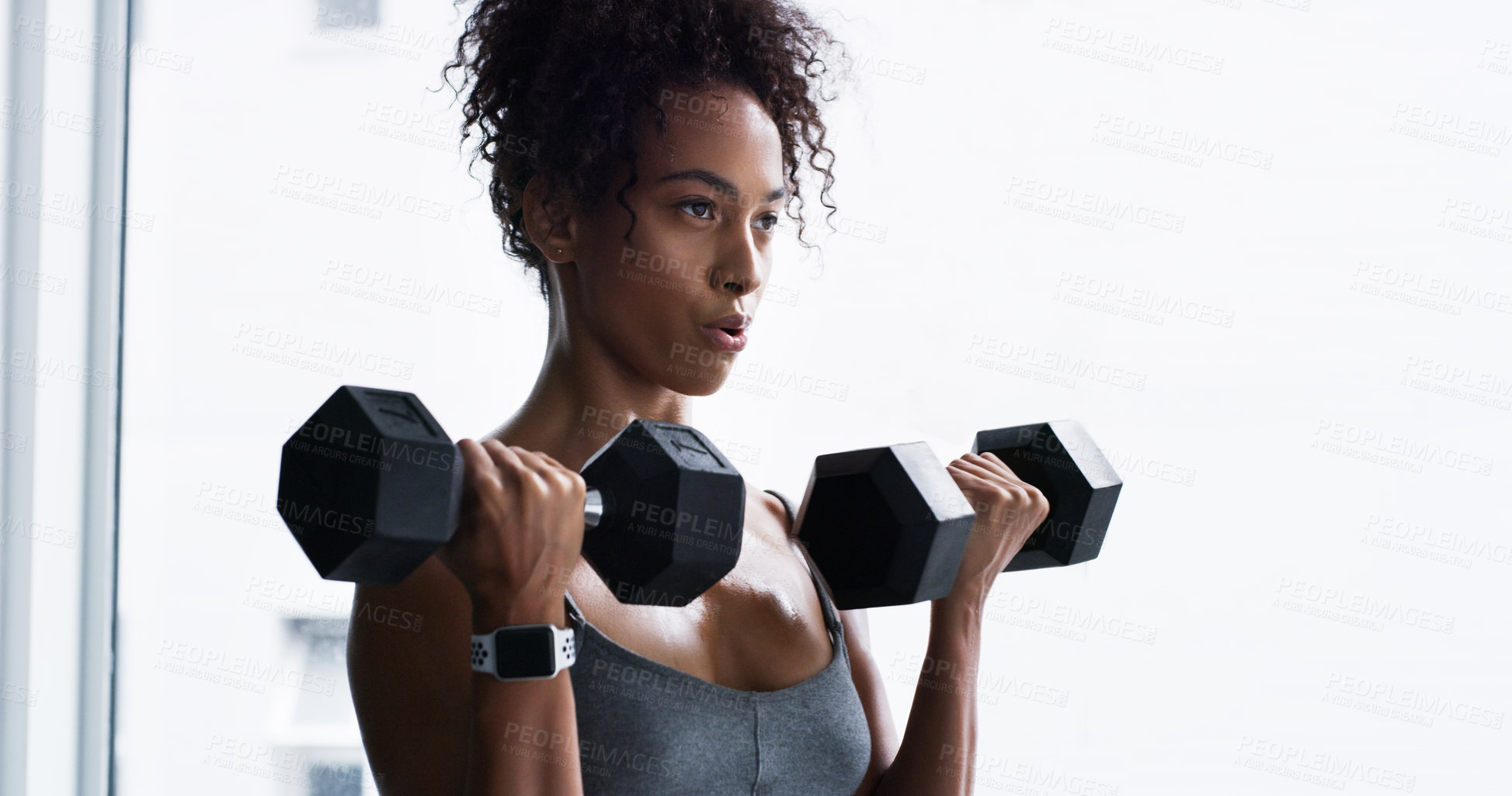 Buy stock photo Shot of a young woman working out with dumbbells in a gym