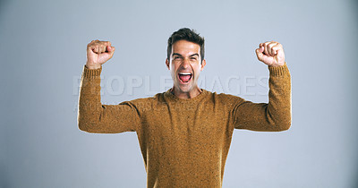 Buy stock photo Studio shot of a handsome young man cheering against a gray background