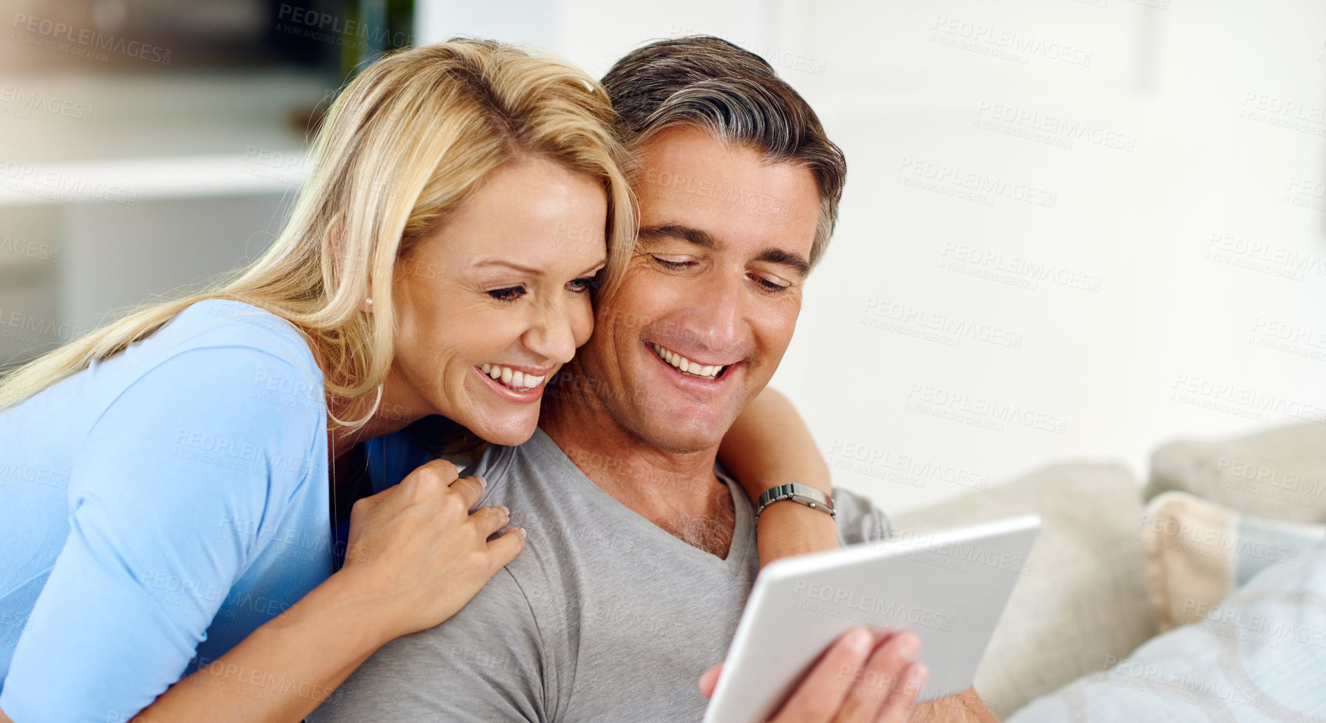 Buy stock photo Cropped shot of a mature couple using a digital tablet while relaxing on the sofa at home