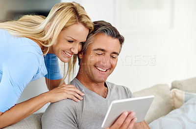 Buy stock photo Cropped shot of a mature couple using a digital tablet while relaxing on the sofa at home