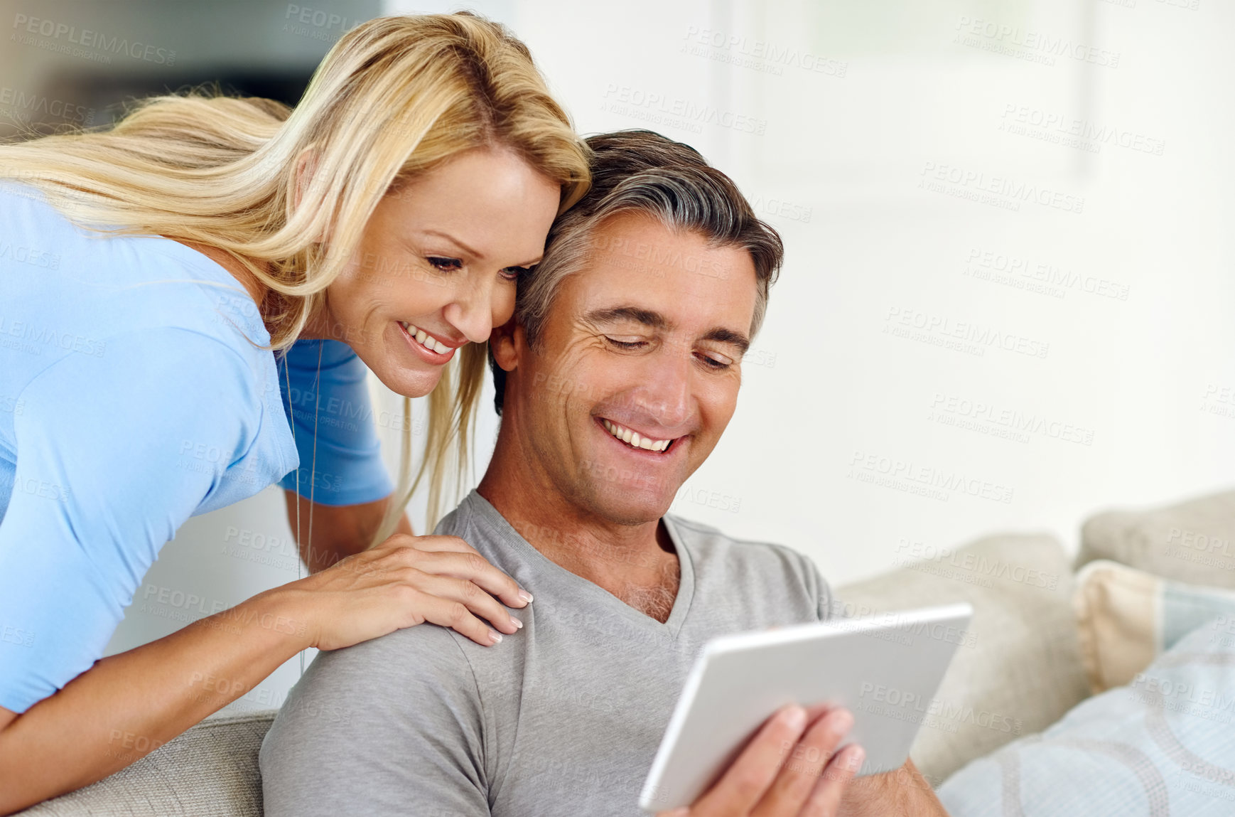 Buy stock photo Cropped shot of a mature couple using a digital tablet while relaxing on the sofa at home
