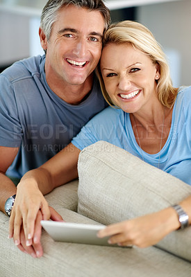 Buy stock photo Cropped portrait of an affectionate couple smiling while using a digital tablet at home
