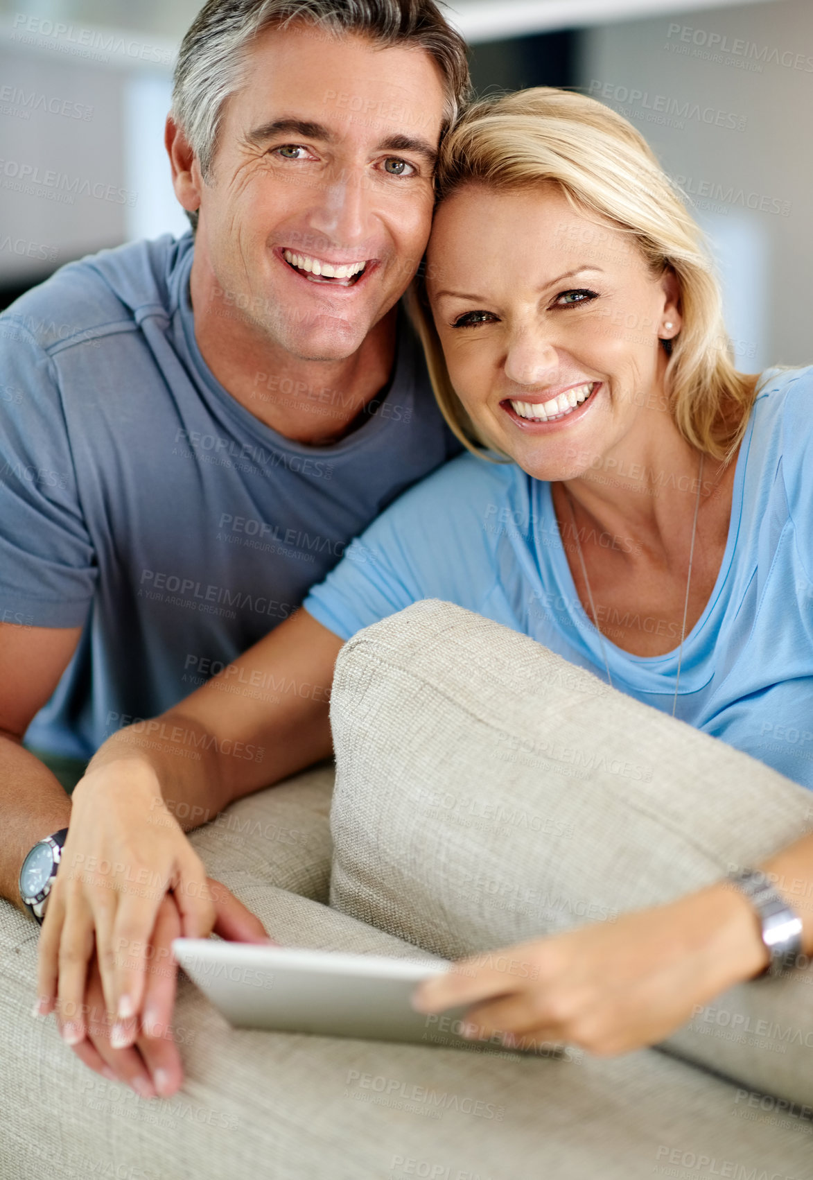 Buy stock photo Cropped portrait of an affectionate couple smiling while using a digital tablet at home