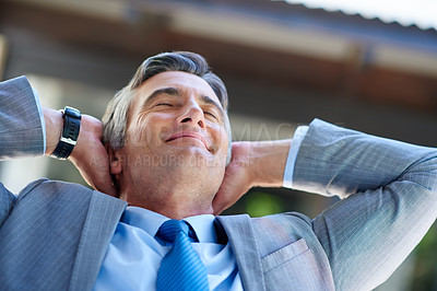 Buy stock photo Cropped shot of a handsome mature businessman looking content with his hands behind his head