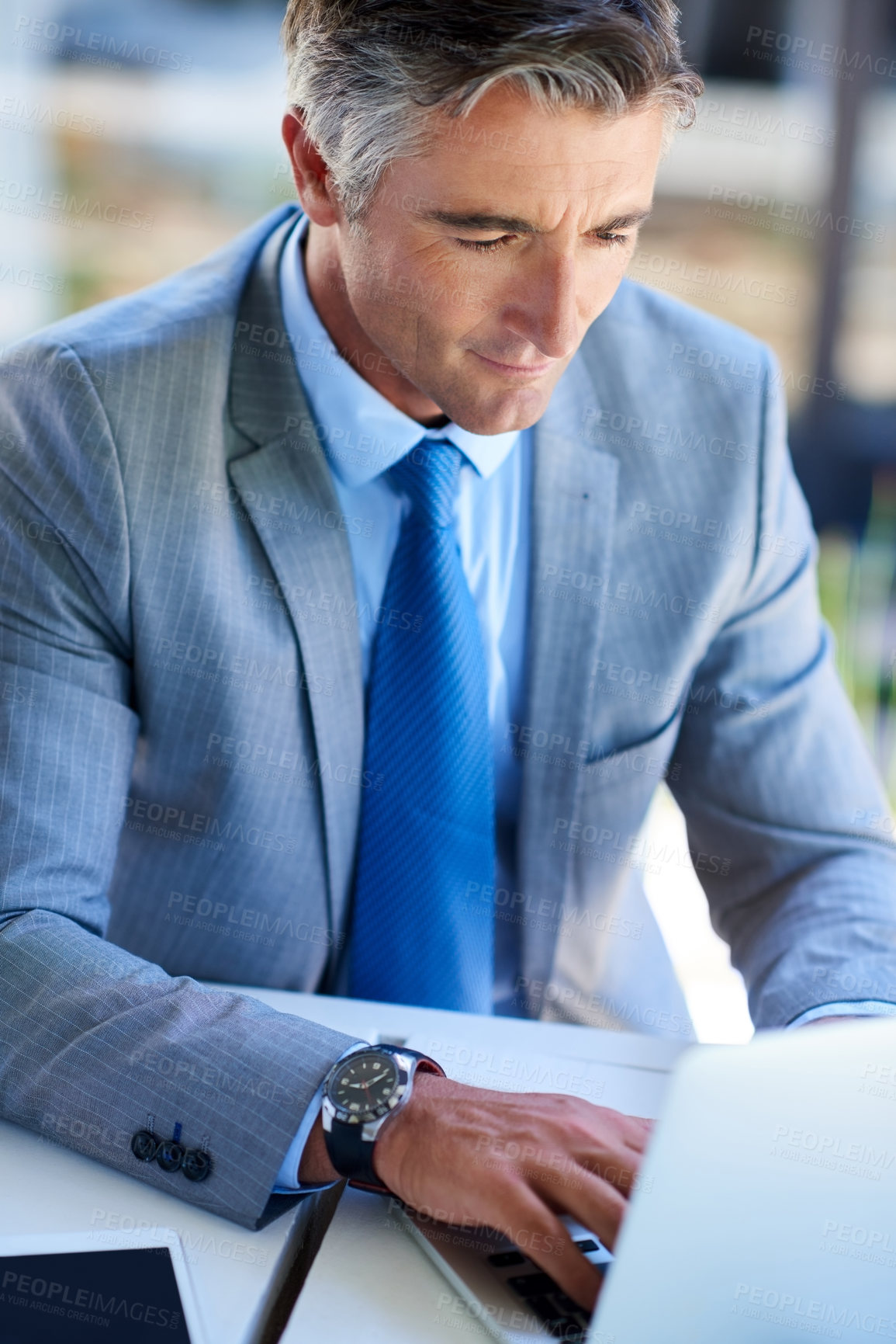 Buy stock photo Cropped portrait of a handsome mature businessman working on a laptop outdoors