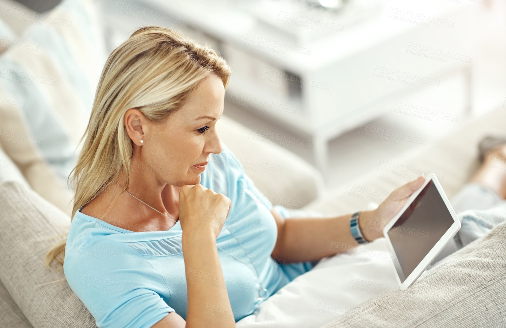 Buy stock photo Cropped shot of an attractive mature woman relaxing on the sofa with a digital tablet