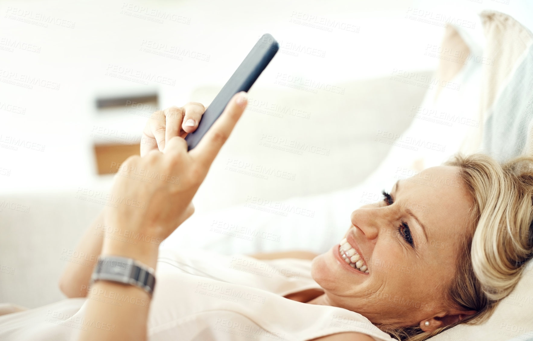 Buy stock photo Mature woman, phone and home on sofa with smile for reading, contact or streaming on mobile app in living room. Person, happy and smartphone for social media, subscription or chat on couch in house