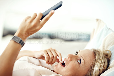 Buy stock photo Cropped shot of an attractive mature woman looking surprised while reading a text message at home