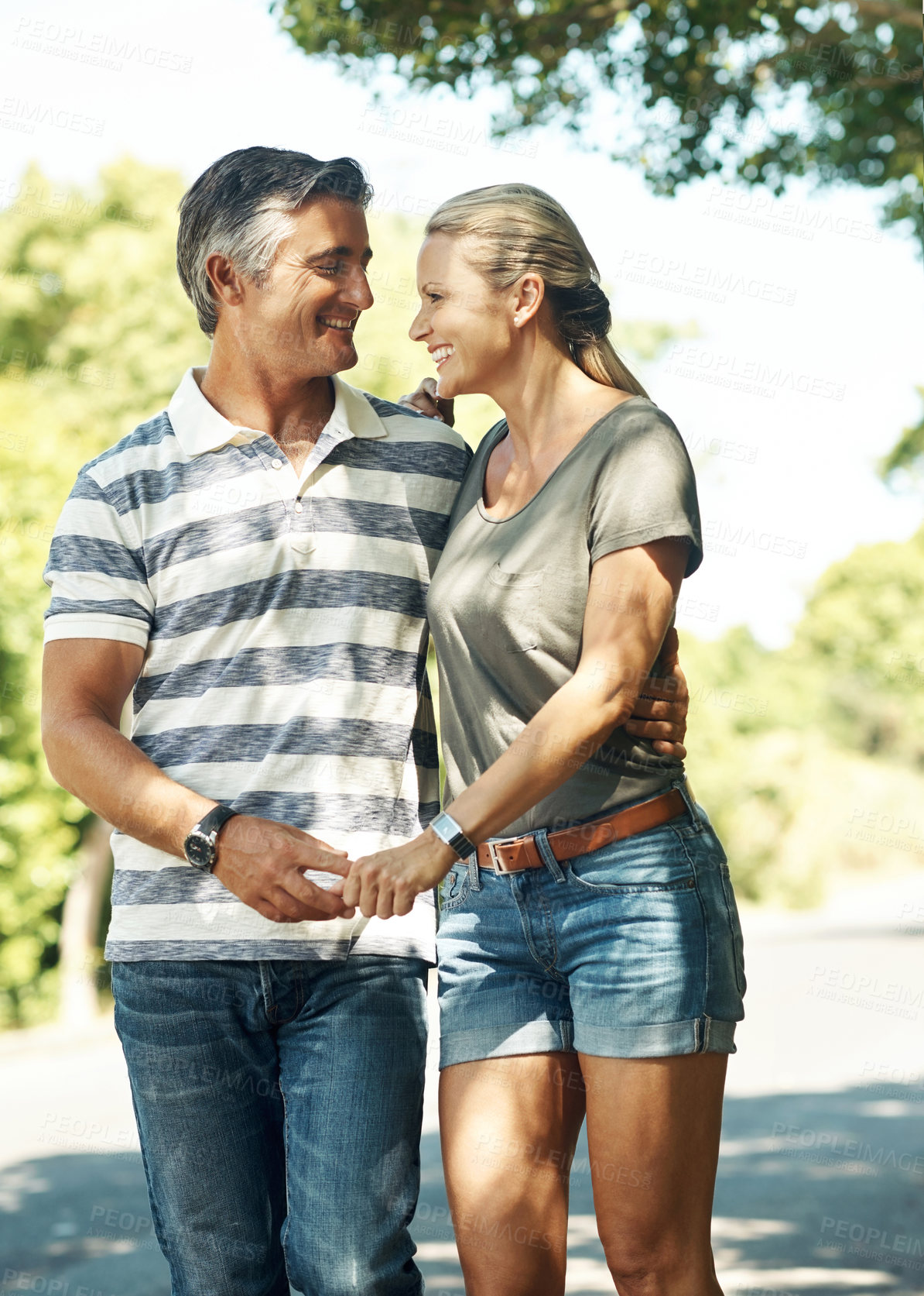 Buy stock photo Happy, holding hands and couple in street walking for bonding, relationship and love outdoors. Nature, marriage and man and woman laugh in park for romance, affection and relax on weekend together