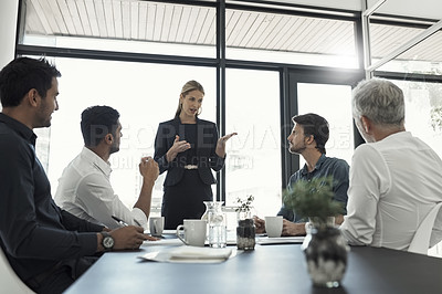 Buy stock photo Cropped shot of a businesswoman talking to colleagues sitting around a table in an boardroom