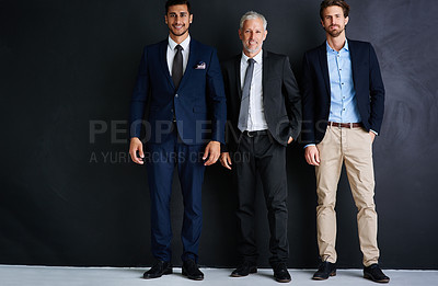 Buy stock photo Studio portrait of three businessman standing against a black background