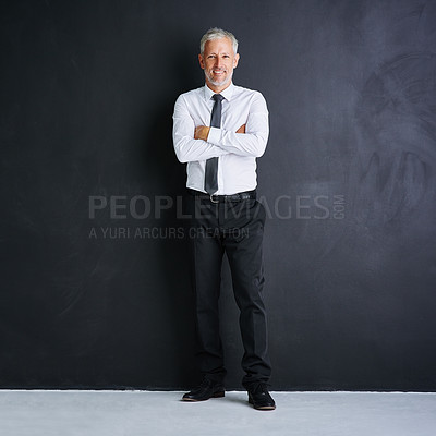 Buy stock photo Studio portrait of a mature businessman standing with his arms crossed against a black background