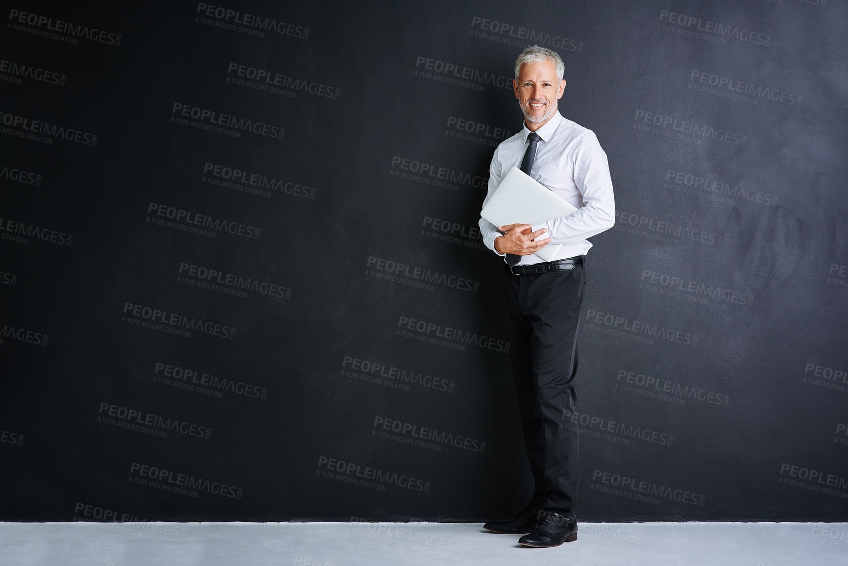 Buy stock photo Studio portrait of a mature businessman standing against a black background